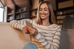 Mulher jovem usando celular para atendimento Desktop via WhatsApp